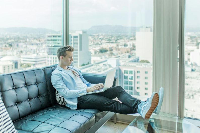 Luxury Brands Deals - man sitting on sofa while using laptop
