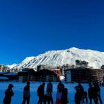 Ski Resorts - a group of people standing on top of a snow covered slope