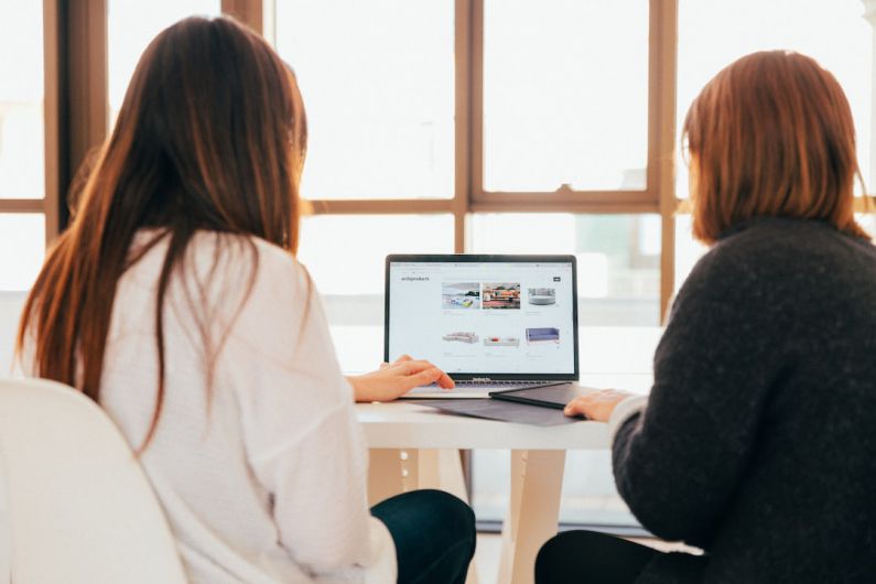 Future Of Remote Work - two women talking while looking at laptop computer